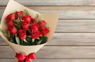 Beautiful bouquet of red roses wrapped in parchment with a red ribbon on wooden background photo