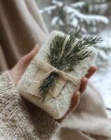 A person holds a beautiful winter bouquet of pine and natural elements in a snowy forest setting photo