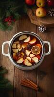 Warm spiced apple cider with cinnamon and dried fruit in a pot on a wooden table photo