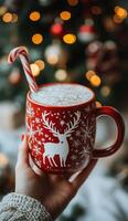 Cozy holiday drink in a festive red mug with a candy cane on a snowy day photo