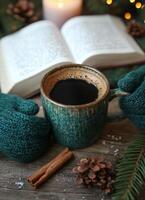 Cozy coffee moment with warm mittens, spices, and a book by candlelight in a winter setting photo