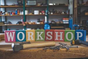 Workshop spelled with colorful wooden blocks on workbench with tools photo