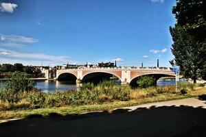 A bridge spanning over a river with trees and grass in London photo