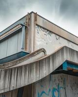 Weathered concrete structure with graffiti, featuring a curved, aging walkway. photo
