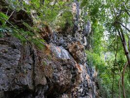 Amazing hillside cliff with compressed layer rock structure of volcanic rock. Close-up texture of volcanic rock. Cracked broken crumbled. photo