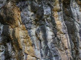 Amazing hillside cliff with compressed layer rock structure of volcanic rock. Close-up texture of volcanic rock. Cracked broken crumbled. photo