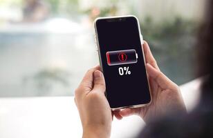Close-up view of woman using mobile phone with battery died notification screen Zero percent remaining. concept of emergency backup battery, Power bank photo