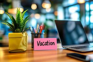 Office table with the message Vacation or holidays written on a note. Laptop and office supplies on blurred background. Out of the office. photo