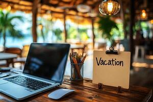Office table with the message Vacation or holidays written on a note. Laptop and office supplies on blurred background. Out of the office. photo