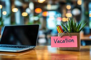 Office table with the message Vacation or holidays written on a note. Laptop and office supplies on blurred background. Out of the office. photo
