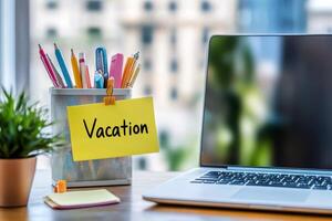 Office table with the message Vacation or holidays written on a note. Laptop and office supplies on blurred background. Out of the office. photo