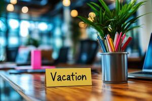 Office table with the message Vacation or holidays written on a note. Laptop and office supplies on blurred background. Out of the office. photo