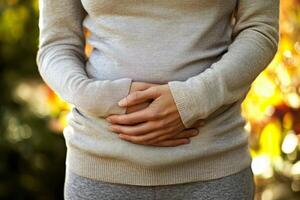 A person with a stomach ache. holding their stomach in pain. on white background. with white space photo
