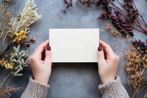 Hand holding printed greeting card mock up, blank empty postcard isolated on natural flower background photo