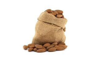 Rustic burlap sack overflowing with fresh almonds isolated on white background photo