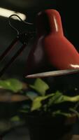 A red desk lamp sitting on top of a wooden table video