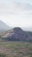 A scenic landscape with a small mound and majestic mountains in the background video