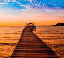 wooden pier that stretches out to the sea of sunset seascape view with cloudy sky for travel in holiday relax time as summer photo