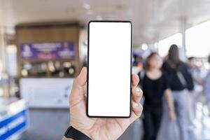 Man's hand holding mobile phone with white empty screen in front of blurry subway photo