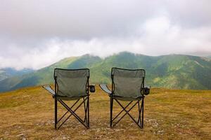 Two camping charis on the hills and misty mountains on the background photo