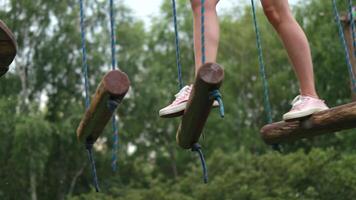 Close-up of a woman's legs running an obstacle course along parallel unstable bars in a rope park. video