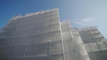 City building with scaffolding covered with transparent foil video