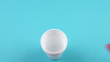 man puts empty disposable cups into stack on light blue video