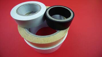 motion around stack of different adhesive tape rolls on red video