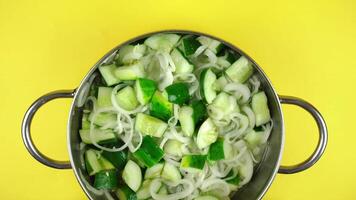Sliced cucumbers with onion in the metal dish on the yellow background video
