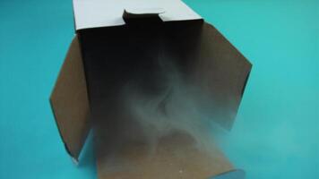steam flows out of open cardboard box on turquoise macro video