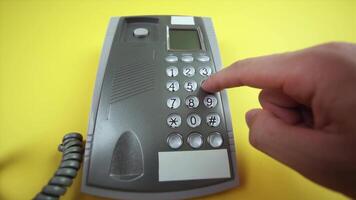 man dials number on corded phone base on yellow background video