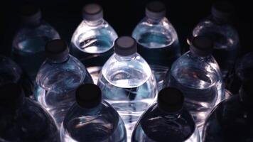bottles with shaken mineral water at light ray at darkness video