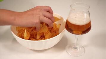 person takes chips of orange colour from white plastic bowl video
