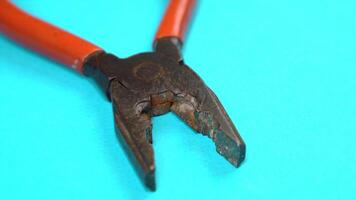 old pliers with plastic handles on azure background macro video
