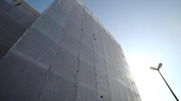 Building scaffolding covered with white protective fabric video