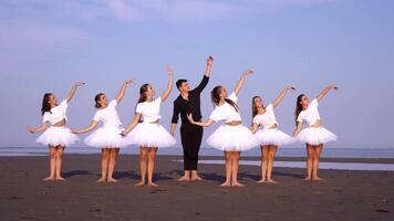 Graceful women with man do ballet exercises on ocean beach video