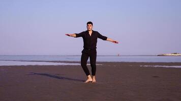 Guy in black performs classic ballet dance on empty beach video