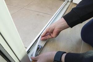 Preparing for the cold season. A man sticks a white foam rubber sealing tape on a door window indoors. Saving Energy Insulating Home Putting Draught Excluder Tape On Window photo