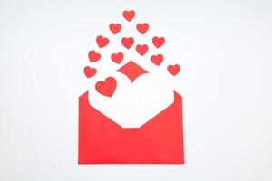 Red envelope with a white sheet of paper and red hearts on a white background. Valentine's day greeting card. photo
