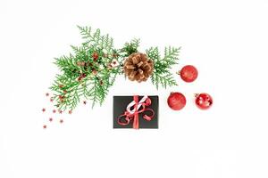 Merry Christmas festive composition with green fir branches, black gift box and red balls with confetti on white background. Flat lay, top view photo