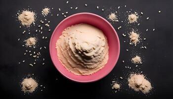 Dry semolina durum flour in a pink bowl over black background, overhead view. Top view, from above, flat lay. Copy space. photo