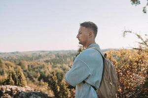 Young happy man hiking in the mountains. A man with a backpack on a hill. photo