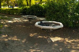 Black white rope circle swing seat at the playground close-up. Black net swing bench on a kids playground. Modern urban environment. photo