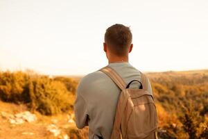 Young happy man hiking in the mountains. A man with a backpack on a hill. photo