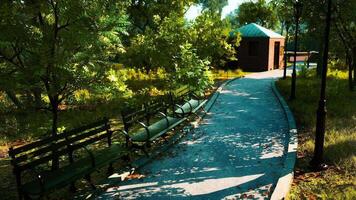 A peaceful park path with benches and a small building in the afternoon light video