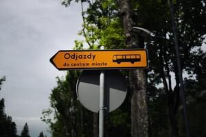 Yellow bus stop sign on the background of tree and blue sky,Information board departure sign on a bus stop. photo