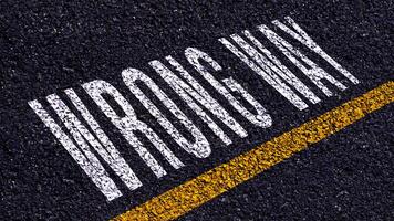 Wrong way, wrong way text written and yellow line on asphalt road ground. photo