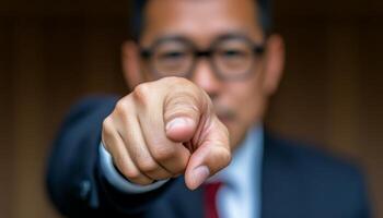 A businessman dressed in a suit points decisively at the viewer, exuding authority photo