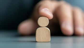 A hand gently holds a wooden figure symbolizing support and identity on a neutral surface photo
