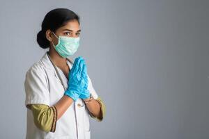 Young woman Doctor doing Namaste because of outbreak of COVID-19. New greeting to avoid the spread of coronavirus instead of greeting with a hug or handshake. photo